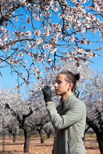 Gardener man smelling flower with essence in tree harvest field