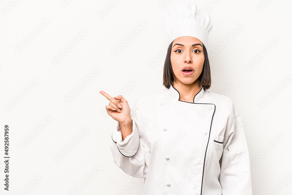 Young hispanic chef woman isolated on white background pointing to the side Young hispanic chef woman isolated on white background pointing to the side