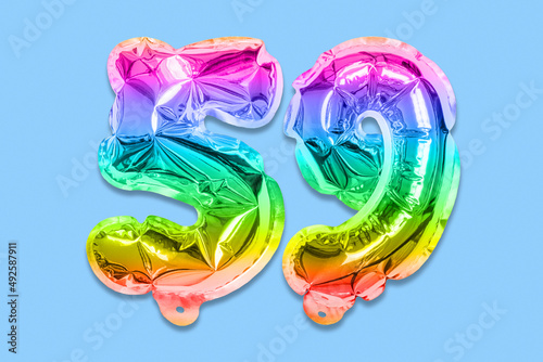 Rainbow foil balloon number, digit fifty nine on a blue background. Birthday greeting card with inscription 59. Top view. Numerical digit. Celebration event, template. photo