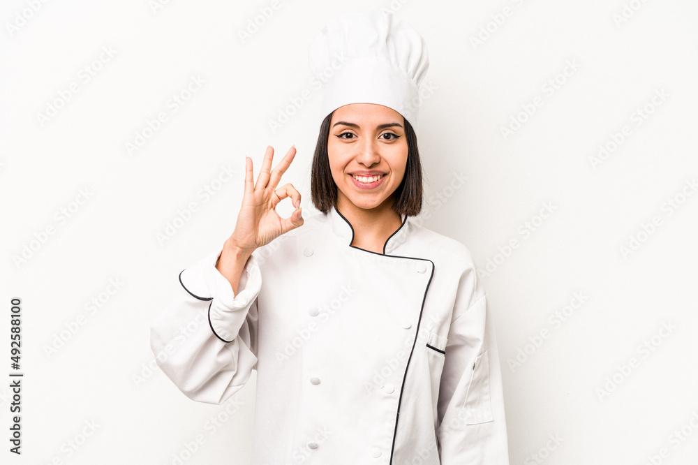 Young hispanic chef woman isolated on white background cheerful and confident showing ok gesture. Young hispanic chef woman isolated on white background cheerful and confident showing ok gesture.