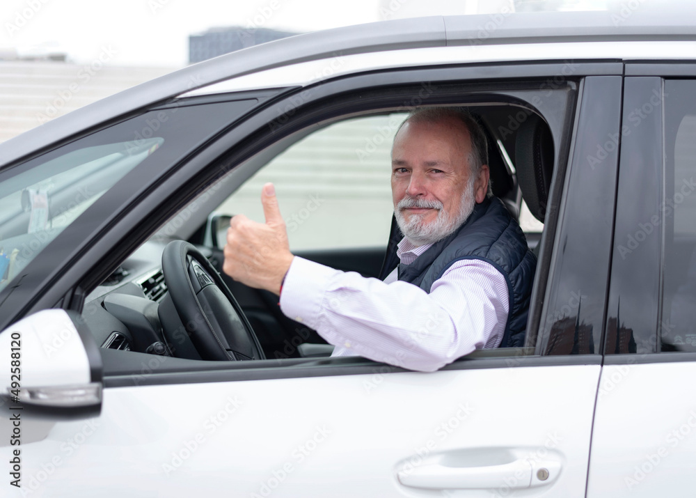 portrait of an elderly driver in car or taxi showing his thumb portrait of an elderly driver in car or taxi showing his thumb