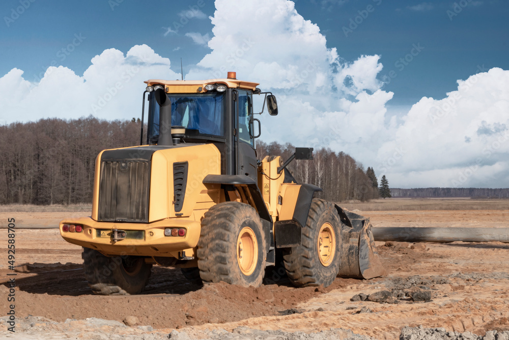 Bulldozer or loader machine is leveling construction site. Earthmover with tractor is moving earth. close-up. construction heavy machinery.