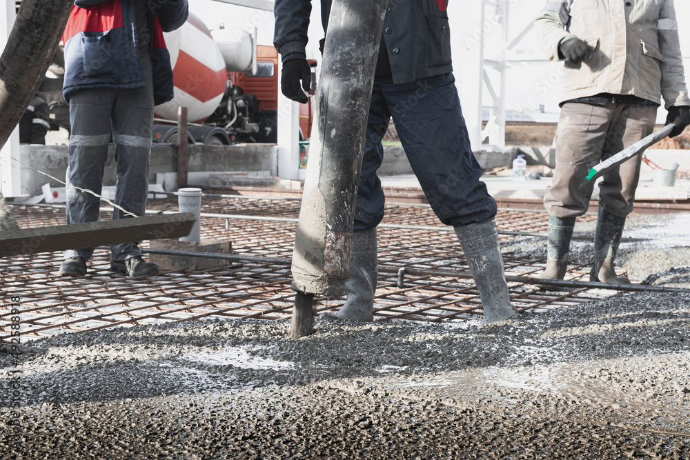 Builders workers pour concrete floor in industrial Legs in