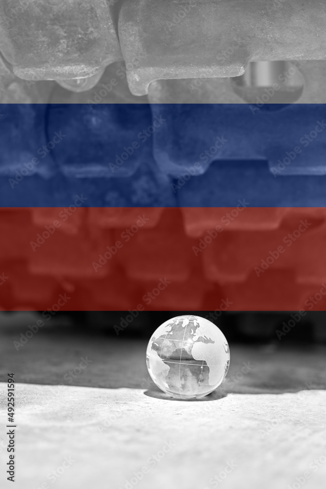 Naklejka premium The glass globe of planet Earth under the tracks of the tank in the colors of the flag of Russia.