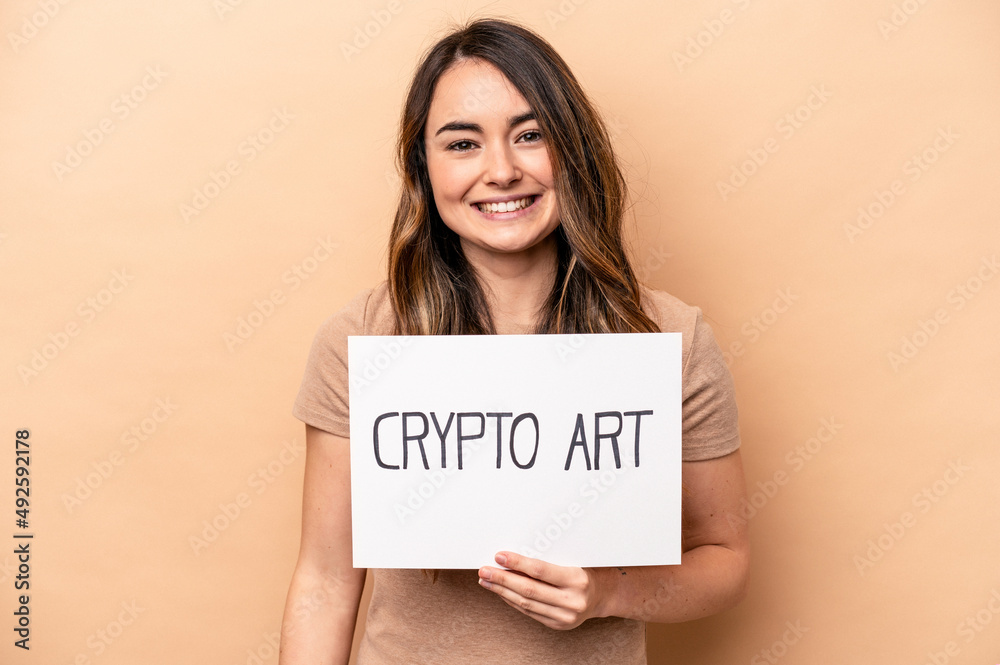 Young caucasian woman holding a crypto art placard isolated on beige background happy, smiling and cheerful. Young caucasian woman holding a crypto art placard isolated on beige background happy, smiling and cheerful.