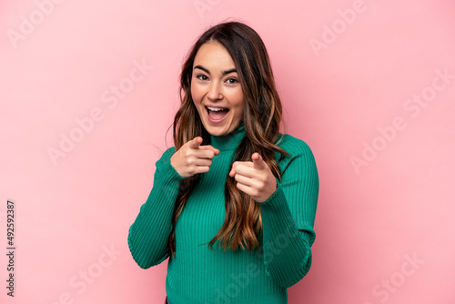 Young caucasian woman isolated on pink background pointing to front with fingers.