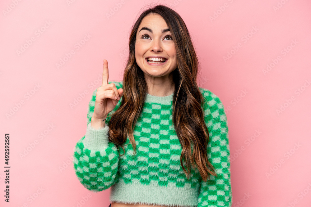 Young caucasian woman isolated on pink background indicates with both fore fingers up showing a blank space. Young caucasian woman isolated on pink background indicates with both fore fingers up showing a blank space.