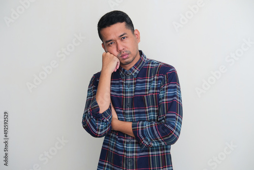 Adult Asian man looking to the camera with sluggish expression photo