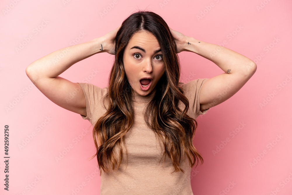 Young caucasian woman isolated on pink background screaming, very excited, passionate, satisfied with something.