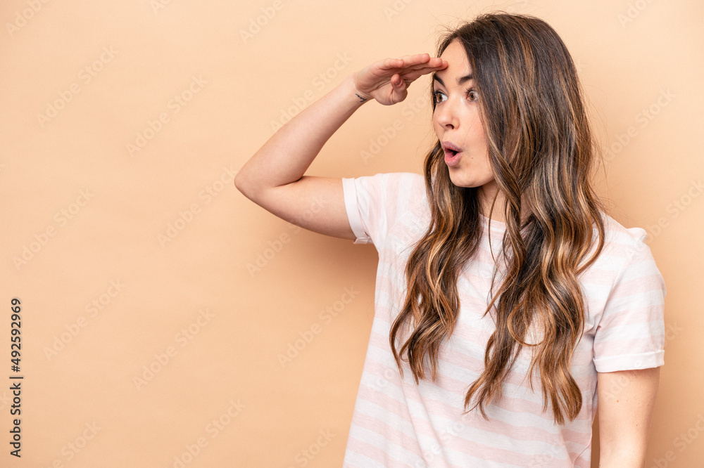 Young caucasian woman isolated on beige background looking far away keeping hand on forehead. Young caucasian woman isolated on beige background looking far away keeping hand on forehead.