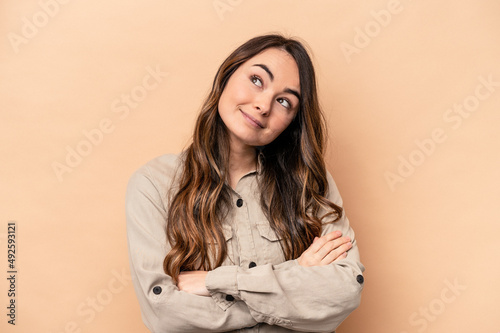 Young caucasian woman isolated on beige background dreaming of achieving goals and purposes