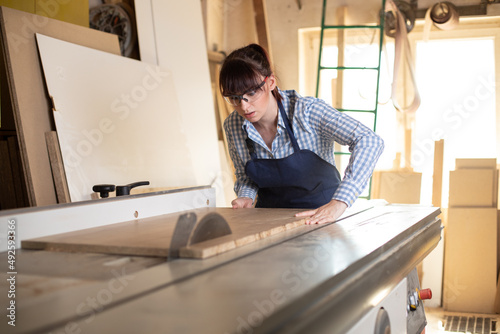 Craftswoman working on the sliding table saw in the carpentry workshop photo