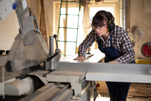 Craftswoman working on the sliding table saw in the carpentry workshop