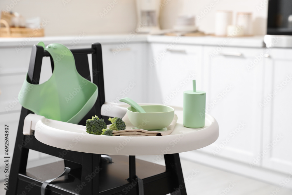 High chair with broccoli and set of baby tableware on tray indoors High chair with broccoli and set of baby tableware on tray indoors