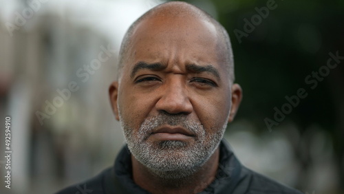 Portrait of a serious senior black man standing outside in street looking at camera