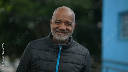 Portrait of a senior black man standing outside smiling in the drizzle rain