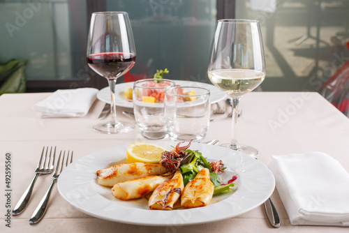 Tavolo di un ristorante elegante fotografato con antipasti di pesce e due calici di vino  photo