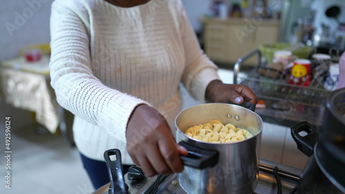 A senior African woman cooking pasta at home stirring pot casual real life