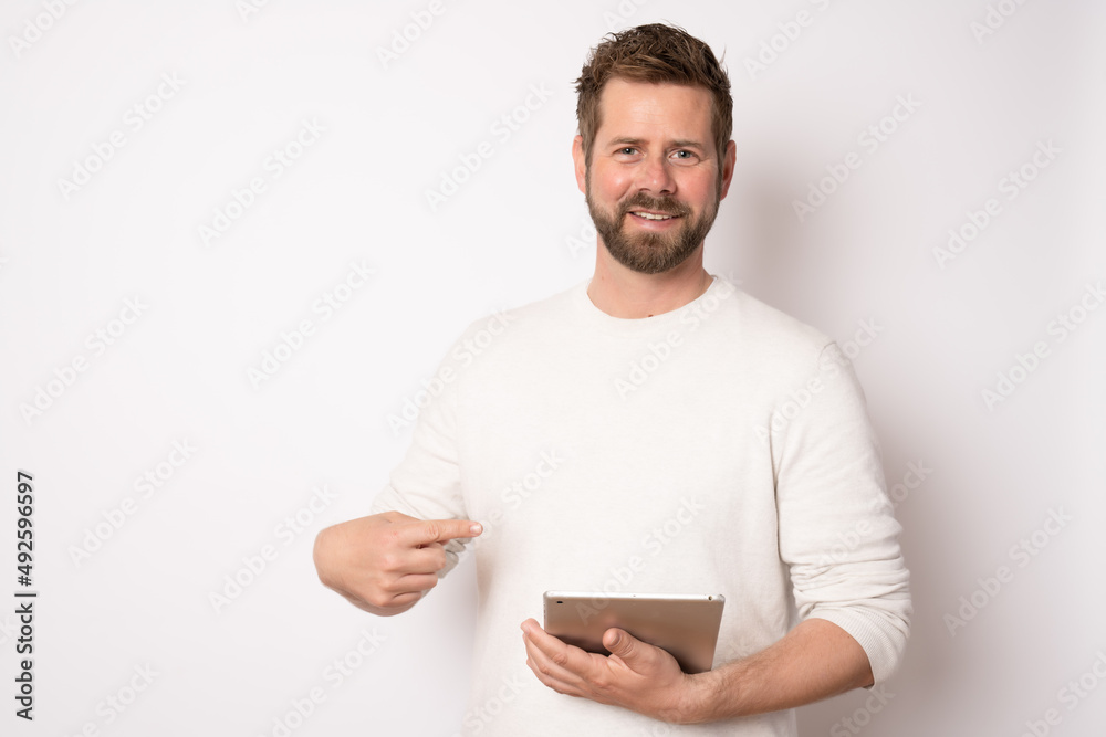 Young man in casual clothes using tablet standing isolated over white background. Business concept. Young man in casual clothes using tablet standing isolated over white background. Business concept.