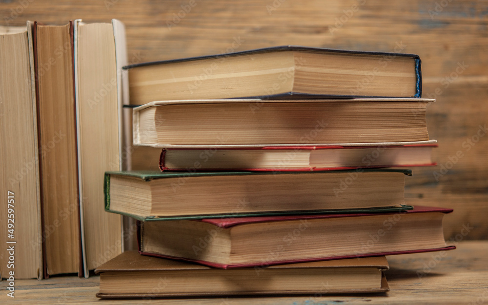 Fototapeta premium Stack of books on wooden table over rustic background with copy space