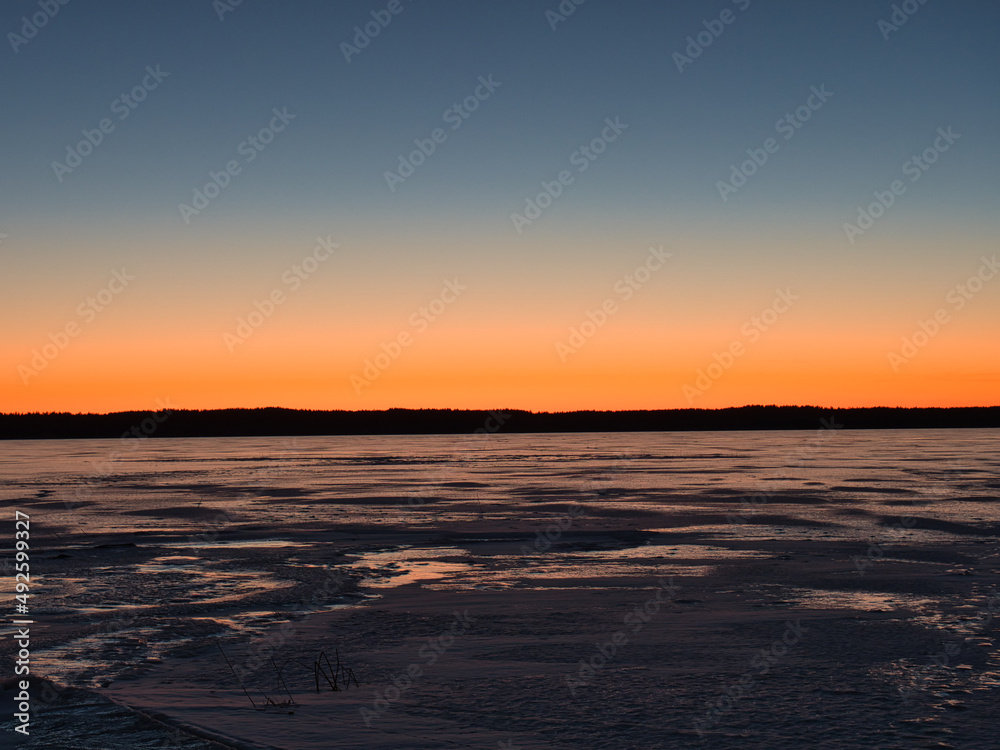 lake in ice in spring against the backdrop of a red sunset
