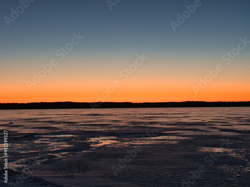 lake in ice in spring against the backdrop of a red sunset