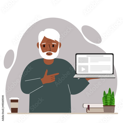 Happy grandfather holding a laptop computer with one hand and pointing at it with the other. Laptop computer technology concept.