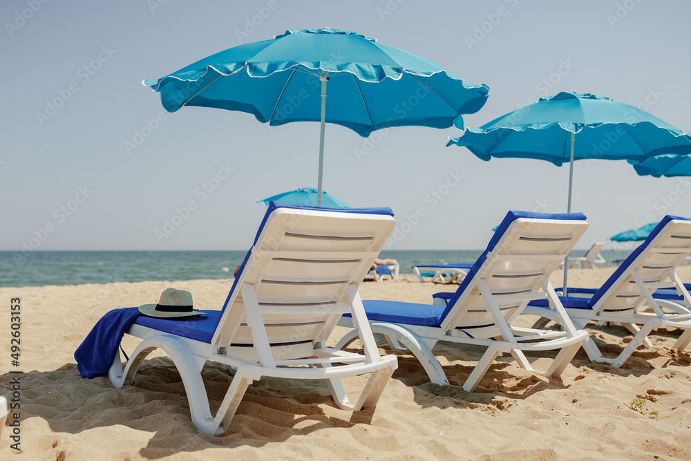 Obraz premium sun loungers on the sand near the sea and umbrellas