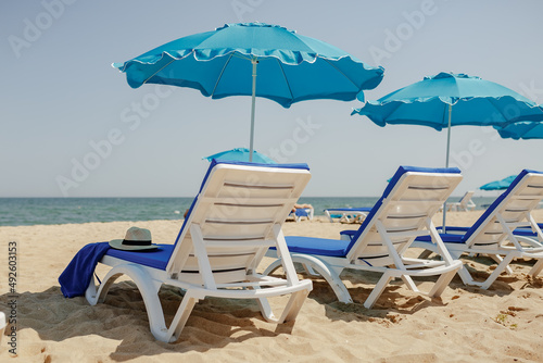 sun loungers on the sand near the sea and umbrellas