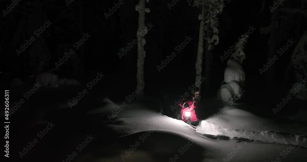 Aerial view following a boy walking in snowy forest, winter night in Lapland - low, tracking, drone shot Aerial view following a boy walking in snowy forest, winter night in Lapland - low, tracking, drone shot