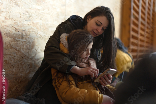 Fototapeta Ukrainian war refugees in temporary shelter and help center, little girl with her mother
