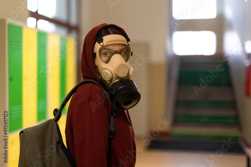 Young student in gas mask looking at camera at school.