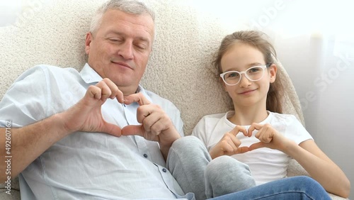 Mature handsome man and little blonde girl are showing hearts by hands, happy family, togetherness, father's day concepts