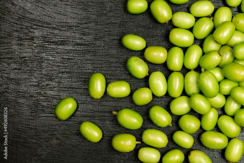 Fresh Neem fruit on black wooden background. Neem fruit is an excellent moisturizing and contains various compounds that have insecticidal and medicinal properties.