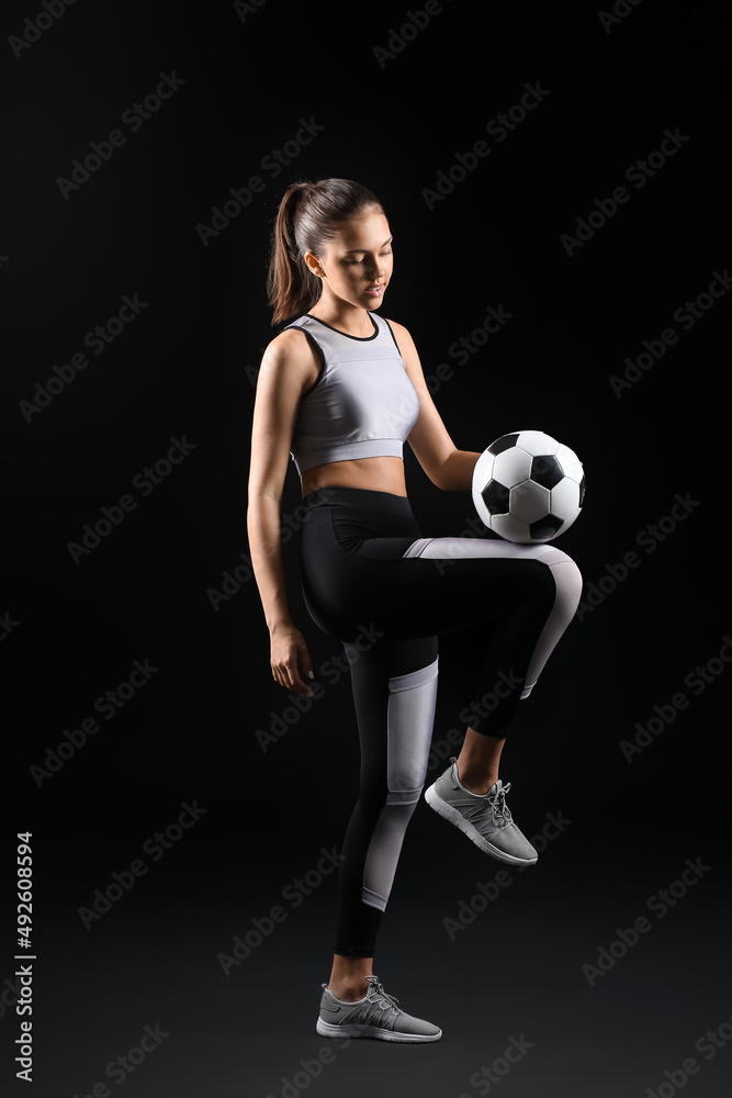 Sporty teenage girl with ball on black background