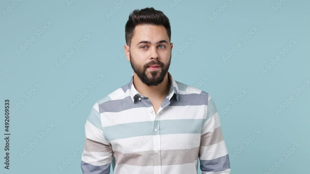 Secret happy fun young bearded brunet man 20s years old wears striped shirt look aside say hush be quiet with finger on lips shhh gesture isolated on plain pastel light blue background studio portrait Secret happy fun young bearded brunet man 20s years old wears striped shirt look aside say hush be quiet with finger on lips shhh gesture isolated on plain pastel light blue background studio portrait