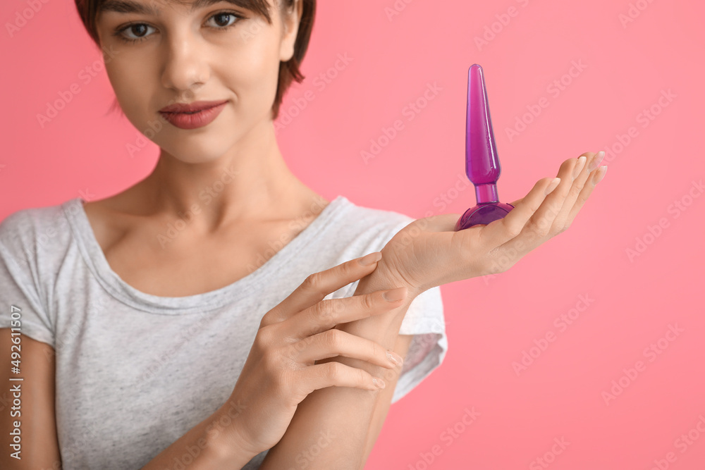 Beautiful young woman with anal plug sex toy on pink background Beautiful young woman with anal plug sex toy on pink background