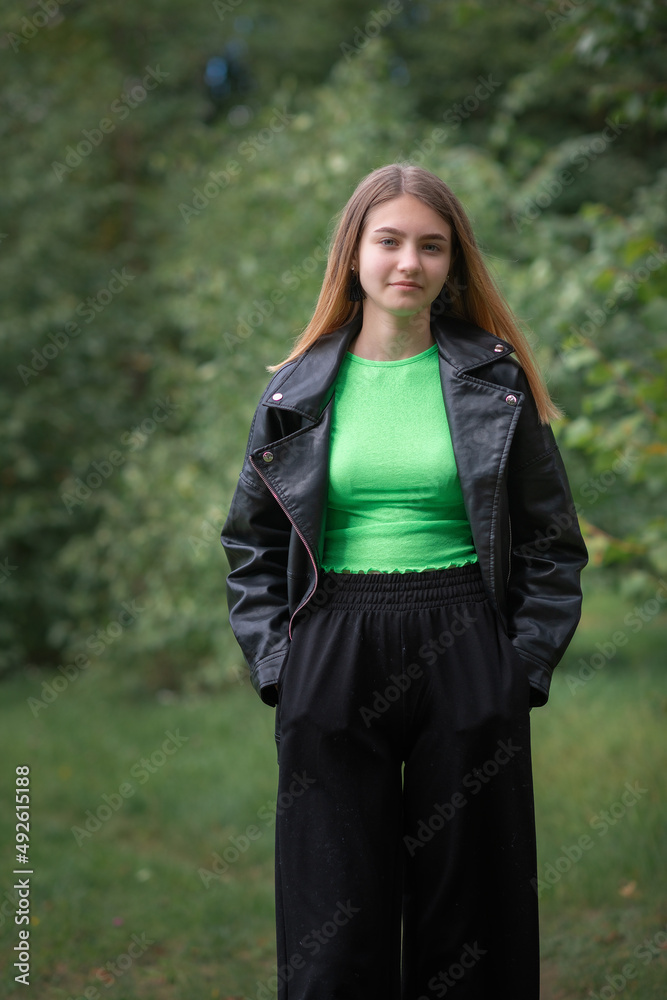 Portrait of a young beautiful blonde girl in dark clothes in a summer park. Portrait of a young beautiful blonde girl in dark clothes in a summer park.