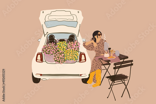 Beautiful woman in dress and rubber boots sitting by the table and drinking hot drink while having picnic near a car full of flowers. Vector illustration