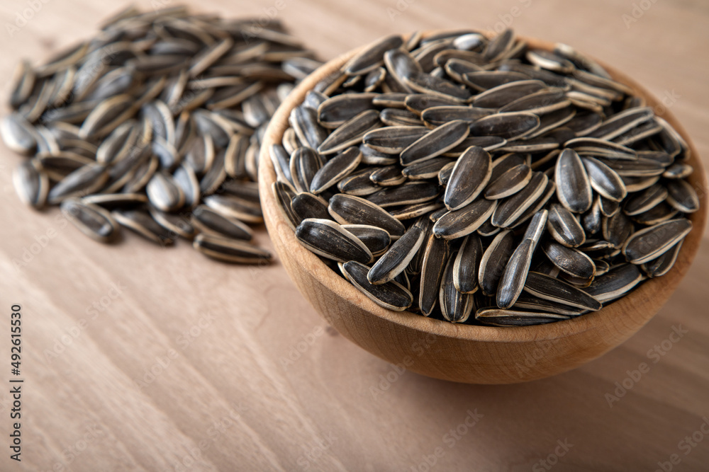 Black sunflower seeds in a bowl on wooden background Black sunflower seeds in a bowl on wooden background