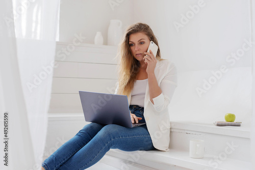 A young girl is sitting in an office in an informal setting with a laptop in her hands.