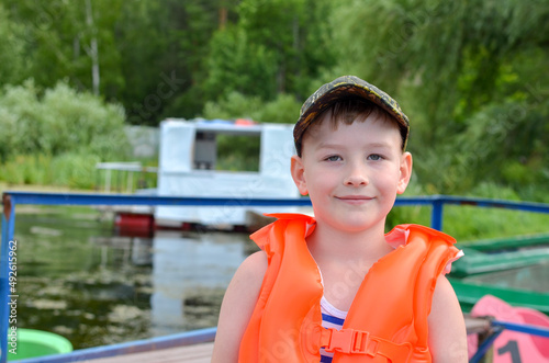 boy in a baseball cap and an orange inflatable life jacket against