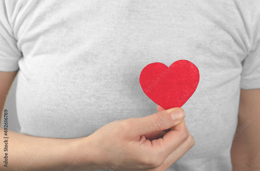 A woman holds a red heart in her hand in front of her. Valentine's Day. World Heart Day.