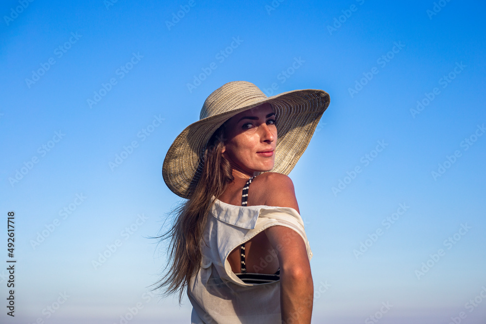 Young sexy woman in hat on blue sky background.
