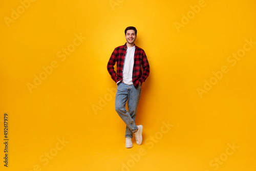 Portrait of happy young man posing at yellow studio