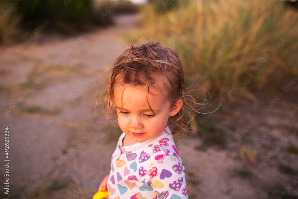 A young girl walks on beach at sunset in pajamas A young girl walks on beach at sunset in pajamas