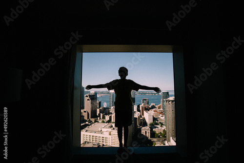 Silhouette of Boy in hotel window against  Cityscape photo