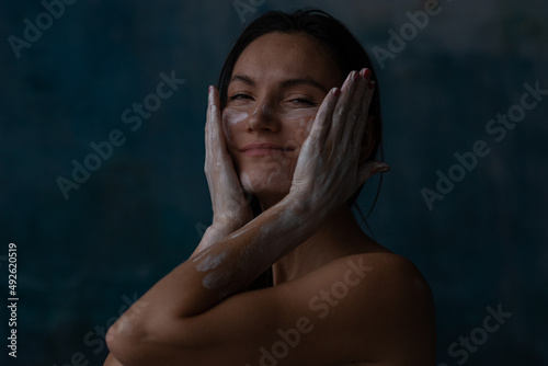Woman drawing face by argil touching by hands and smiling photo