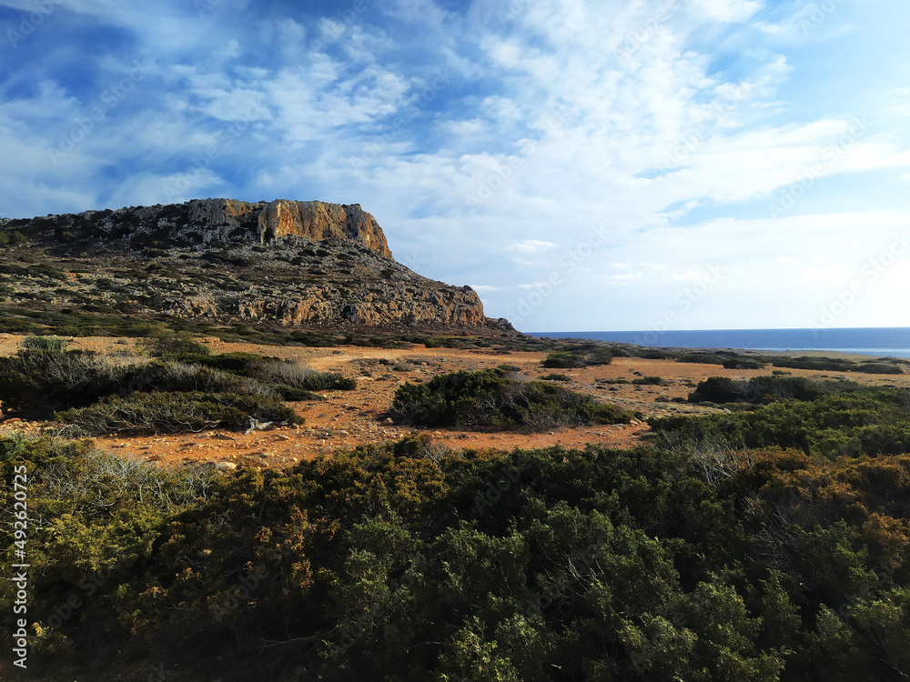 Cape Greco near Ayia Napa. Cyprus, Mediterranean Sea coast. Brown red soil with green bushes near Cavo Greco.