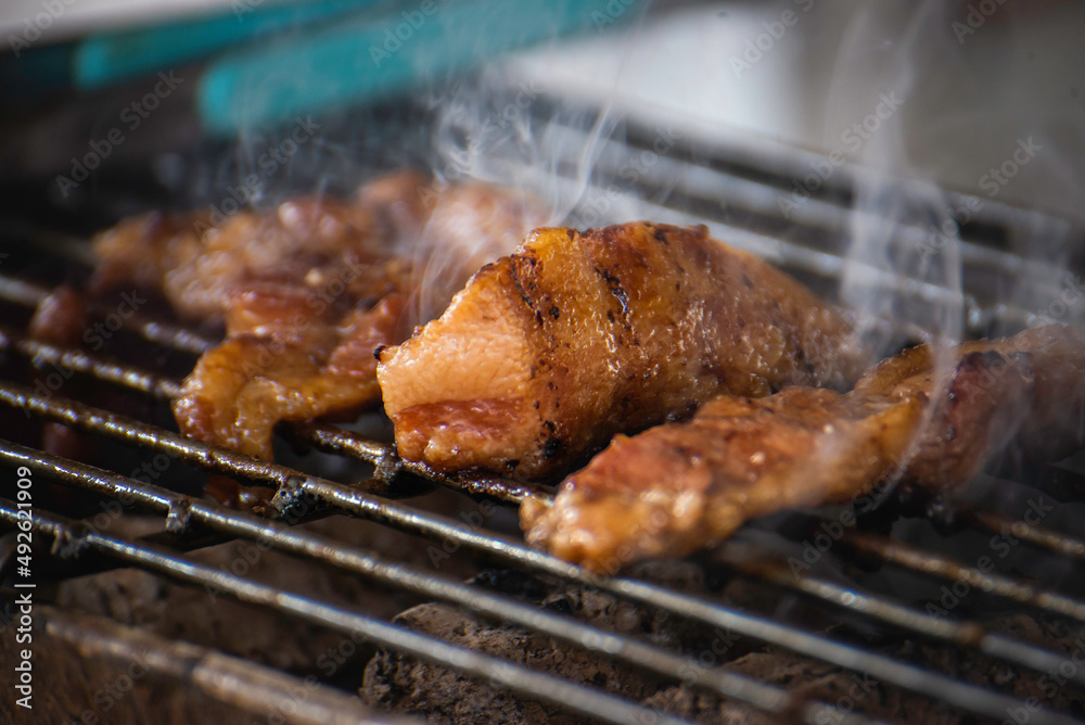 Roasting pork on a charcoal stove with smoke Roasting pork on a charcoal stove with smoke